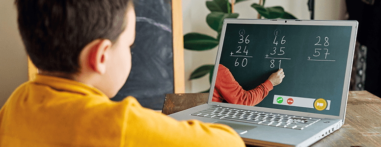 Young boy (6-7) looking at laptop doing  elearning for Math